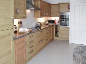 a kitchen with wooden cabinets and stainless steel appliances at Seaglass in Marazion