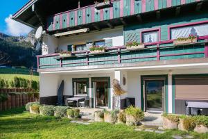 a building with a balcony with tables and windows at Haus am See - Wohnung Königssee in Königssee