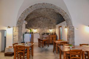 a restaurant with wooden tables and a stone wall at B&B Borgo Sciugolo in Baselice