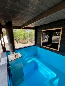 a blue swimming pool with a window in a house at Alaska Tree Tents Linnansaari in Savonlinna