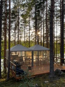 a house in the woods with tables and umbrellas at Alaska Tree Tents Linnansaari in Savonlinna