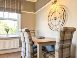 a dining room with a wooden table and a clock on the wall at Cracken Cottage - Uk48297 in Chinley