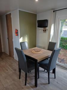 a dining room table with chairs and a tv on the wall at Mobil home 6 personnes 3 chambres in Pont-Aven