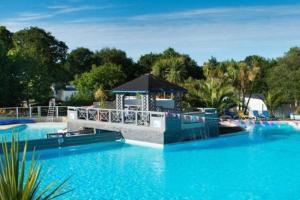 a large swimming pool with a gazebo and blue water at Mobil home 6 personnes 3 chambres in Pont-Aven