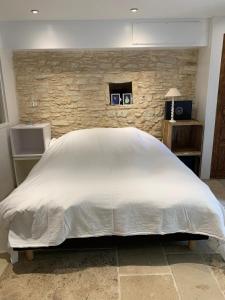 Una gran cama blanca en una habitación con una pared de piedra. en Gîte avec piscine - Rigal haut, en Gindou