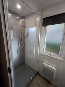a glass shower in a bathroom with a window at Mobil home 6 personnes 3 chambres in Pont-Aven +9 photos