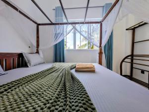 a bedroom with a bed and a window at Costels Mirissa in Mirissa