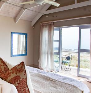 een slaapkamer met een bed en een groot raam bij SableChateau Beachfront Guesthouse in Stompneusbaai +20 foto's