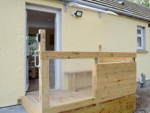 a wooden building with a window on the side of a house at Harland Cottage in Castletown