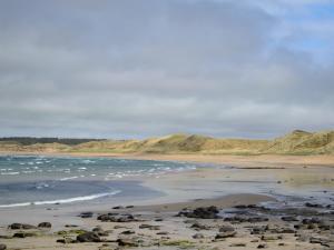 a beach with rocks and the ocean and hills at Harland Cottage in Castletown +4 photos