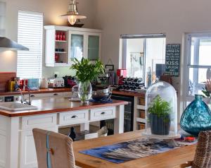 een keuken met witte kasten en een houten tafel bij SableChateau Beachfront Guesthouse in Stompneusbaai