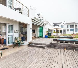 een patio van een huis met een houten terras bij SableChateau Beachfront Guesthouse in Stompneusbaai