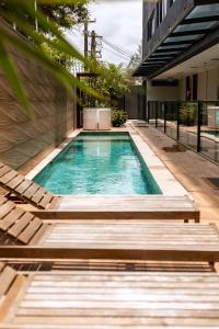 a swimming pool with two chairs and a building at Easy Porto Hotel in Porto De Galinhas