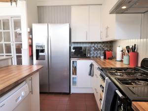 een keuken met witte kasten en een roestvrijstalen koelkast bij The Camber in Cowes +26 foto's