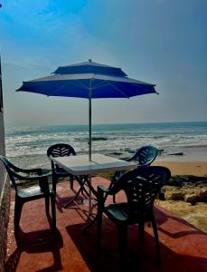 a table and chairs with an umbrella on the beach at beachfront house in Taghazout +16 photos
