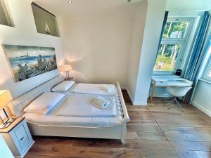 a bedroom with a bed and a desk and windows at Appartement Baltic Pearl in Ostseebad Sellin