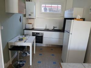 a small kitchen with a table and a refrigerator at T2 avec terrasse privative in Le Havre