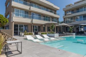 an apartment building with a swimming pool and lounge chairs at Selena Beach Family Hotel - All Inclusive Light in Sozopol +88 photos