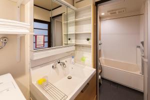 Un baño con lavabo, espejo y bañera. en Shiori 栞 京都, en Kioto