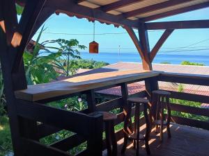 une table et des tabourets en bois sur une terrasse donnant sur l'océan dans l'établissement Ti kaz morne marigot, à Vieux-Habitants