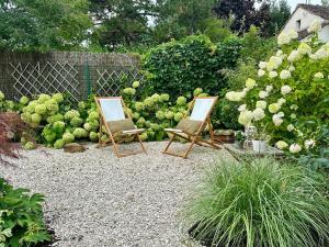 two empty chairs sitting in a garden with flowers at Suite Cosy Barbizon in Barbizon +21 photos