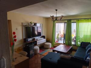 a living room with a blue couch and a tv at A pasos de la playa in Algarrobo