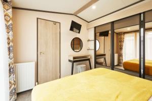 a bedroom with a yellow bed and a mirror at Royal Pines Lodge with Hot tub in Allerthorpe +25 photos