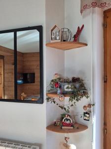 een kamer met een spiegel en planken met kerstversieringen bij Duplex au Col du Corbier in Le Biot