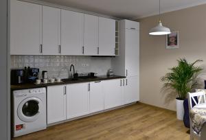 a kitchen with white cabinets and a washing machine at Apartamenty Milano in Tarnobrzeg