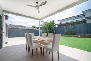 eine Terrasse mit einem Holztisch und weißen Stühlen in der Unterkunft Spacious Retreat with Balcony Patio and Family Comfort in Doolandella