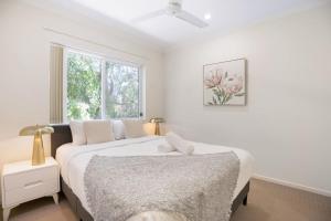 ein weißes Schlafzimmer mit einem Bett und einem Fenster in der Unterkunft Affordable Cosy Retreat with Balcony, AC, and Parking in Springwood