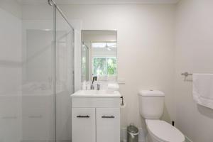 ein weißes Badezimmer mit Toilette und Dusche in der Unterkunft Affordable Cosy Retreat with Balcony, AC, and Parking in Springwood