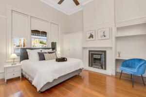 a white bedroom with a bed and a blue chair at Retreat on Chaffey in Mildura +72 photos