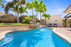 einen Pool mit Palmen und ein Haus in der Unterkunft Coastal Paradise in Tanki Lender