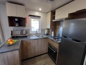 a kitchen with a stainless steel refrigerator and a bowl of fruit at Mobil home 6 personnes 3 chambres in Pont-Aven