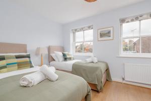 a bedroom with two beds and two windows at Saxon Mews in Wareham