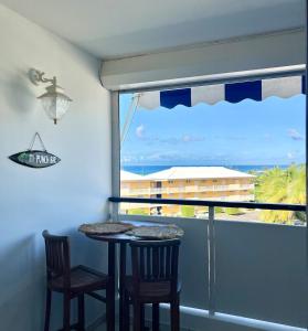 a balcony with a table and two chairs and a window at Studio vue mer avec un accès plage à 1 min in Le Moule