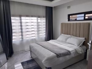 een slaapkamer met een groot bed en een raam bij T & M Apartments in Ndola