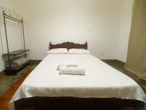 a large white bed with two towels on it at kitnet no centro histórico in São João del Rei