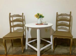 a white table with two chairs and a vase with flowers at kitnet no centro histórico in São João del Rei +9 photos
