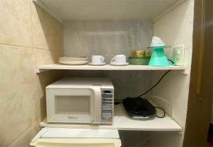 a microwave oven sitting on a shelf in a kitchen at kitnet no centro histórico in São João del Rei