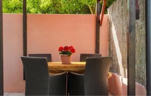 une table avec des chaises et un vase avec des fleurs rouges. dans l'établissement 1 Bedroom Beautiful Apartment In Fazana, à Fažana