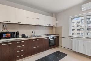 a kitchen with white cabinets and a sink and a window at Modern 1BR Retreat Cofee & Peace in Bucharest