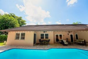 a house with a swimming pool in front of it at Poolside Miami Paradise with BBQ & Outdoor Lounge in Country Walk