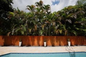 a fence with palm trees and a swimming pool at Poolside Miami Paradise with BBQ & Outdoor Lounge in Country Walk