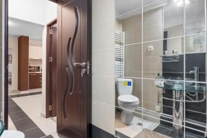 a bathroom with a toilet and a glass door at Modern 1BR Retreat Cofee & Peace in Bucharest