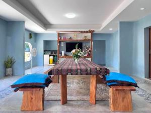 een eettafel met twee blauwe stoelen met kussens en een tafel met een av bij 7Sea Beach Pool Villa in Ao Nam Mao