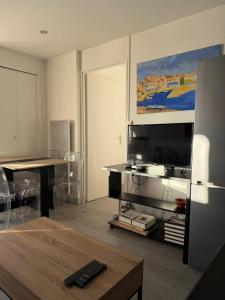 ein Wohnzimmer mit Fernseher und Tisch in der Unterkunft River City - Joli 2 pièces, étage élevé, vue sur port et mer, calme et proche des plages in Mauguio