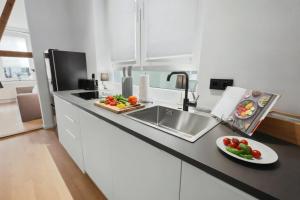 a kitchen with a sink and a plate of vegetables on a counter at MILPAU Herne1 - Zentrales, modernes Design-Apartment - Smart TV, Nespresso für 4 Personen in Herne +8 photos