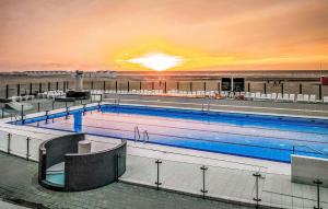 ein großer Pool mit Sonnenuntergang im Hintergrund in der Unterkunft 3 Bedroom Gorgeous Home In Koksijde in Galopen + 18 Fotos